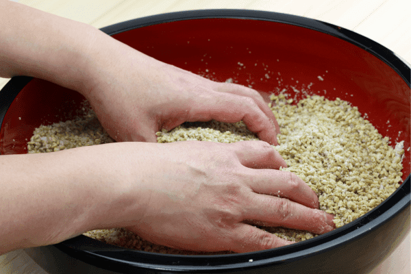 Mãos misturando ingredientes secos para preparo de nutrientes hidropônicos naturais