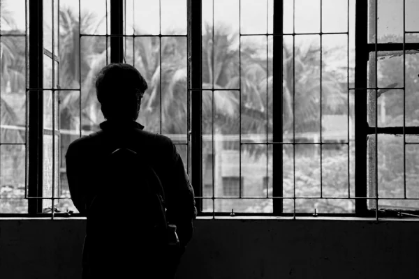 Pessoa em silêncio diante de uma janela, simbolizando atenção como recurso em estado de recolhimento