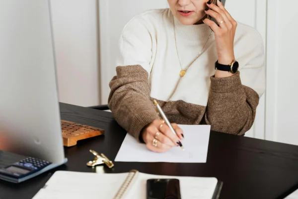 Pessoa trabalhando enquanto fala ao telefone, dividindo a atenção entre múltimas tarefas